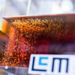 Nahansicht eines durchsichtigen Ölbehälters mit LCM-Logo, ein Exponat des Linz Center of Mechatronics